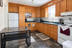 A kitchen with wooden cabinets, a microwave, a stove, and a sink. - Rest Easy in Dildo | By the Sea | South Dildo (South Dildo)