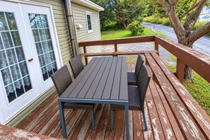 A wooden deck with a table and chairs, a railing, and a house with a garage door. - Rest Easy in Dildo | By the Sea | South Dildo (South Dildo)