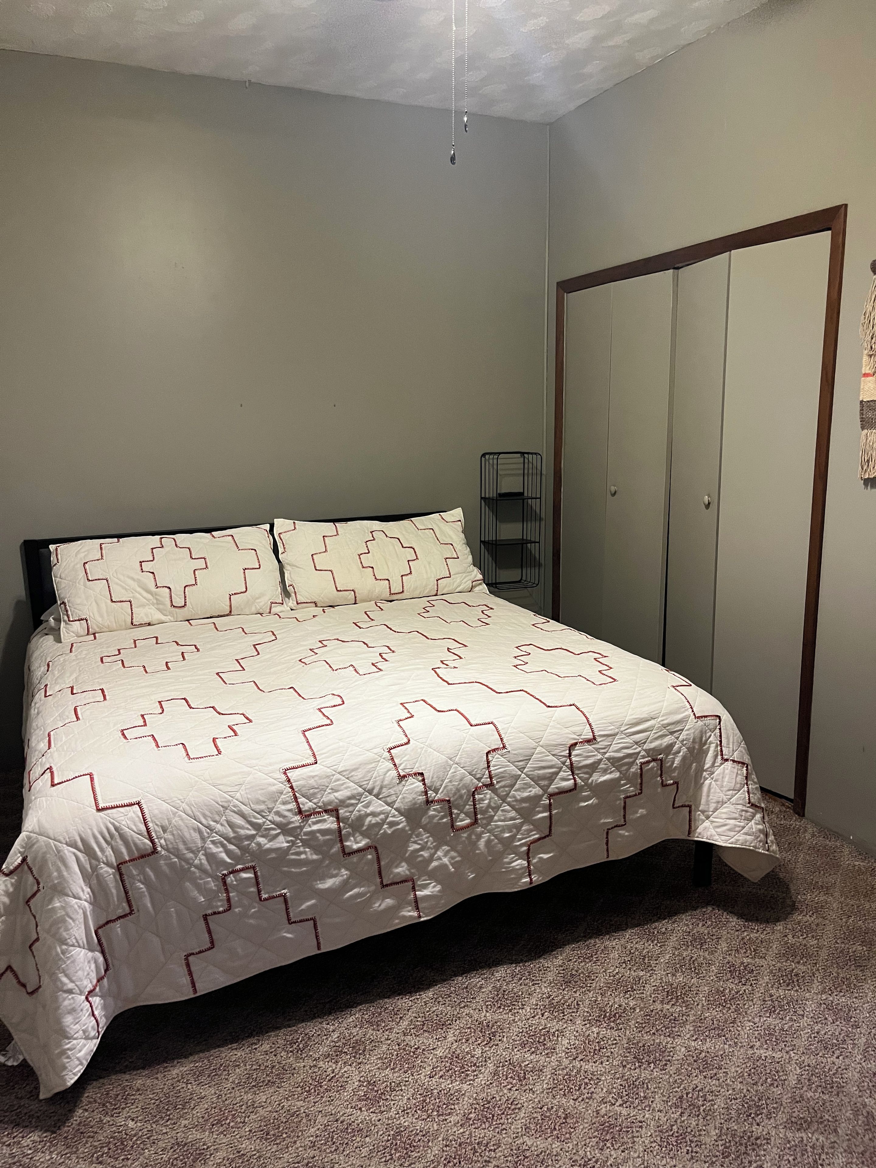 Un dormitorio con cama, armario e iluminación colgante.