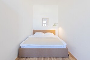 A neatly made bed with a headboard, a framed picture on the wall, and a bedside lamp. - 1-Bedroom Apartment with Air Conditioning | Landstraße | 4 Guests (Wien)
