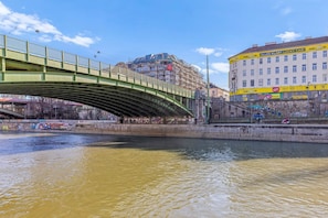 A green bridge over a river with buildings and graffiti on the sides. - 1-Bedroom Apartment with Air Conditioning | Landstraße | 4 Guests (Wien)