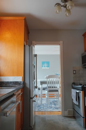 A kitchen with wooden cabinets, a stainless steel refrigerator, and a microwave. - The Little River Retreat - Riverfront (St. Clair)