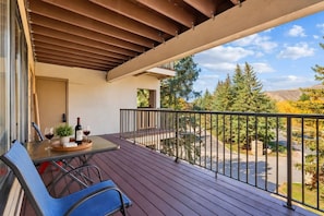 Ein Balkon mit Tisch und Stühlen, einer Weinflasche und einem Weinglas.