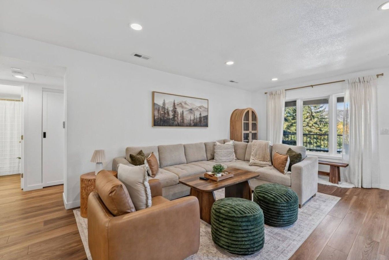 A modern living room with a sectional sofa, a coffee table, and a large window with curtains.