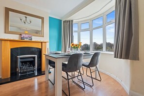 A modern kitchen with a fireplace, a dining table with chairs, and large windows offering a view of the outside. - 3BR 3Bath Solihull | JLR • NEC • Airport • Parking (Solihull)