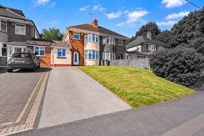 A residential property with a driveway, a car parked on the left, and a well-maintained lawn. - 3BR 3Bath Solihull | JLR • NEC • Airport • Parking (Solihull)