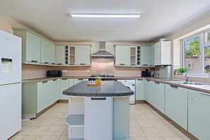 A modern kitchen with a central island, built-in appliances, and a view of the outdoors. - 3BR 3Bath Solihull | JLR • NEC • Airport • Parking (Solihull)
