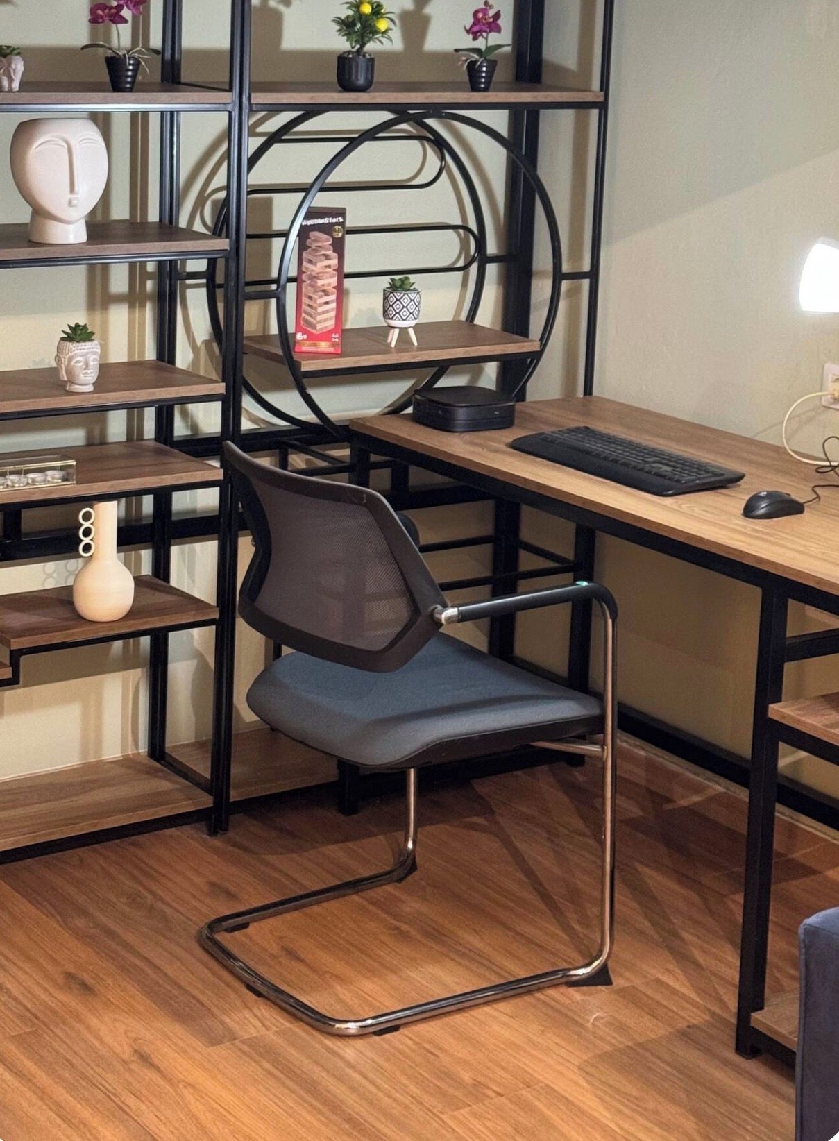 Ein moderner Arbeitsbereich mit Schreibtisch, Stuhl, Regalen und Dekorationselementen.