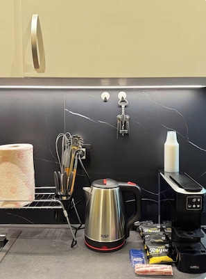 A kitchen with a black countertop, a stainless steel kettle, a roll of paper towels, a coffee machine, and a set of keys hanging on the wall. - A comfortable duplex in Fresku, Tirana. (Tiranë)