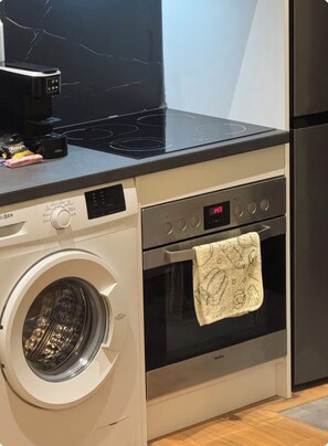 A compact kitchen with a washing machine, an oven, and a stovetop. - A comfortable duplex in Fresku, Tirana. (Tiranë)