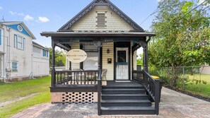 A two-story building with a porch, a sign reading 'Vintage Riverside Cottage,' and a staircase leading to the entrance. - The Gilded Jaguar - w/King Bed in Riverside (Jacksonville)