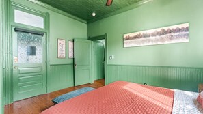 A room with a bed, a door, a window, and a wall-mounted picture. - The Gilded Jaguar - w/King Bed in Riverside (Jacksonville)
