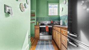 A kitchen with a stove, oven, microwave, and refrigerator. There is a window above the sink and a door on the right. - The Gilded Jaguar - w/King Bed in Riverside (Jacksonville)