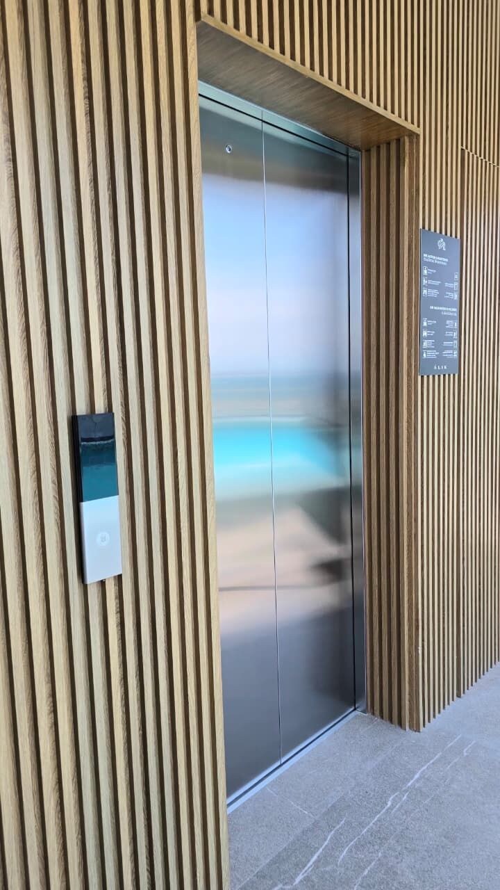 Une entrée moderne, avec un revêtement mural vertical en bois, une porte en verre et une enseigne.