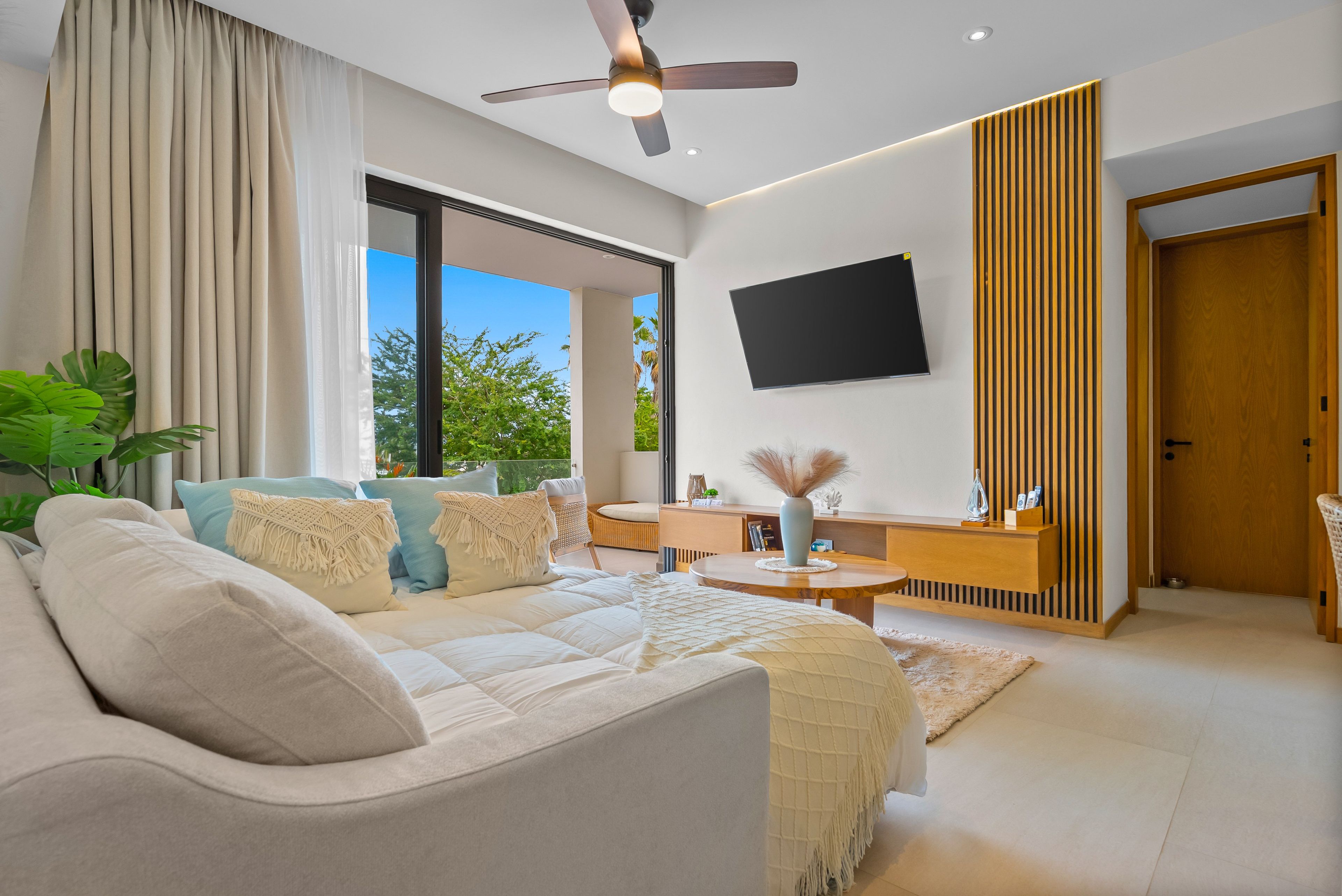 Ein modernes Wohnzimmer mit einer Couch, einem flachbildfernseher an der Wand und einem Deckenventilator.