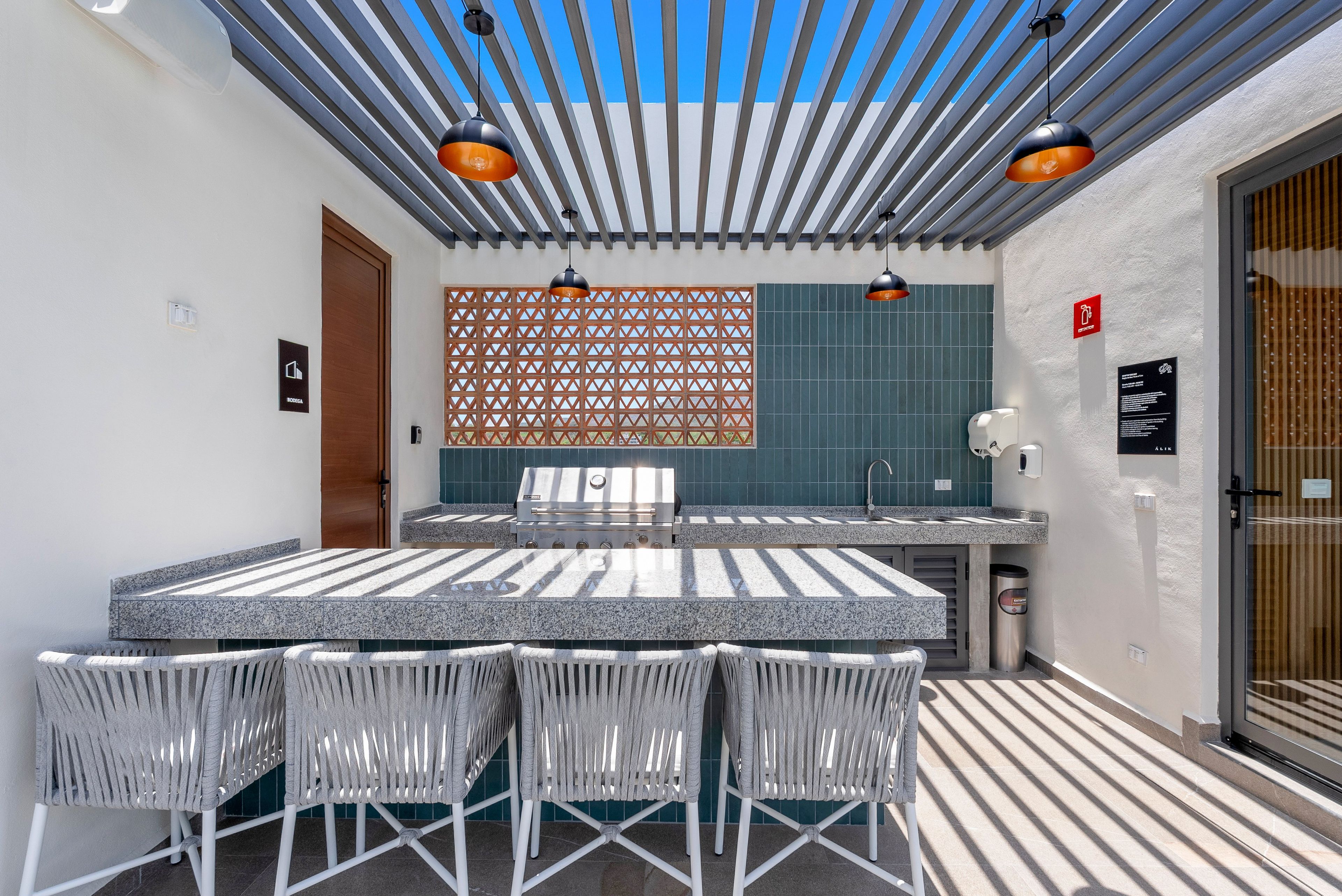 Un patio al aire libre con mesa y sillas, una parrilla y un techo con diseño.