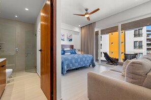 A modern hotel room with a bed, a seating area, and a balcony with a view of the building. - Luxury 2BR Lock-off Rooftop Pool Golden Zone (Bucerías)