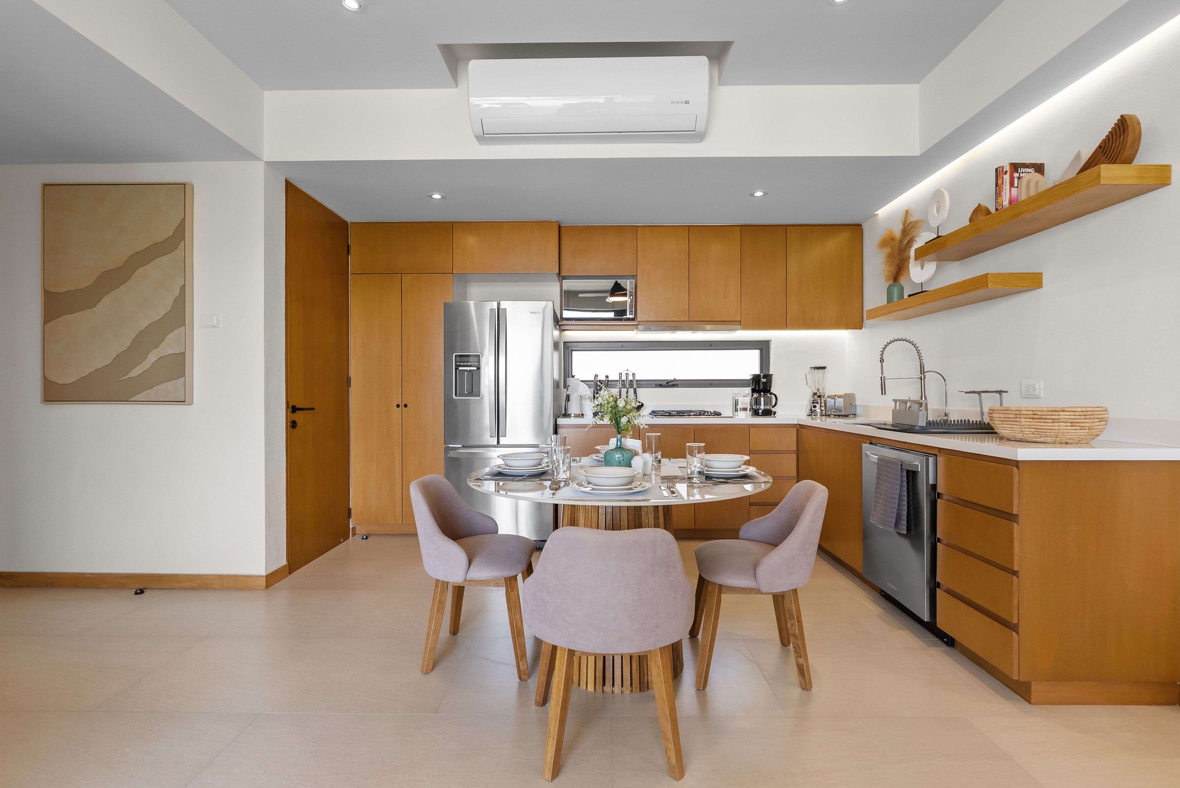 A modern kitchen with wooden cabinets, stainless steel appliances, and a dining area with a round table and chairs.