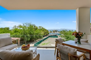 A balcony with a view of a marina, outdoor furniture, and a dining table. - New Home 3BR Condo Near the Ocean With Pool, Gym, AC, and Full Kitchen (La Cruz de Huanacaxtle)