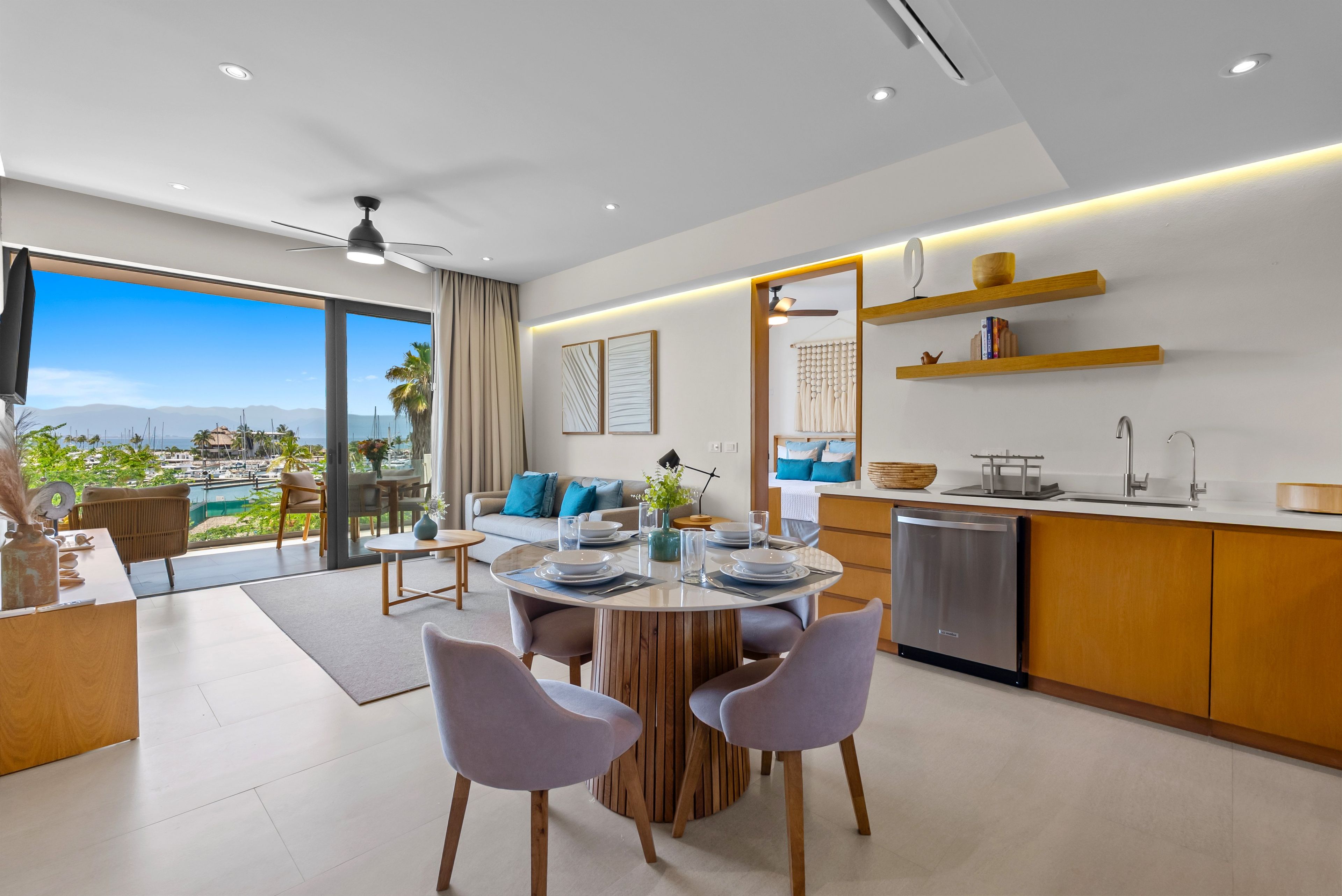 A modern interior with a dining area, kitchen, and a balcony with a view.
