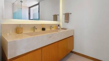A bathroom with a large mirror, a countertop with toiletries, and wooden cabinets.