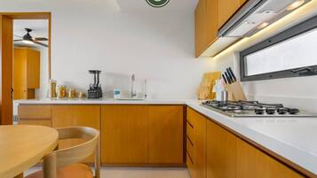 A modern kitchen with wooden cabinets, a gas stove, and a dining area with a table and chairs.