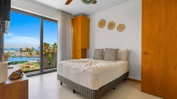Un dormitorio con una cama grande, vistas al mar y un armario de madera.