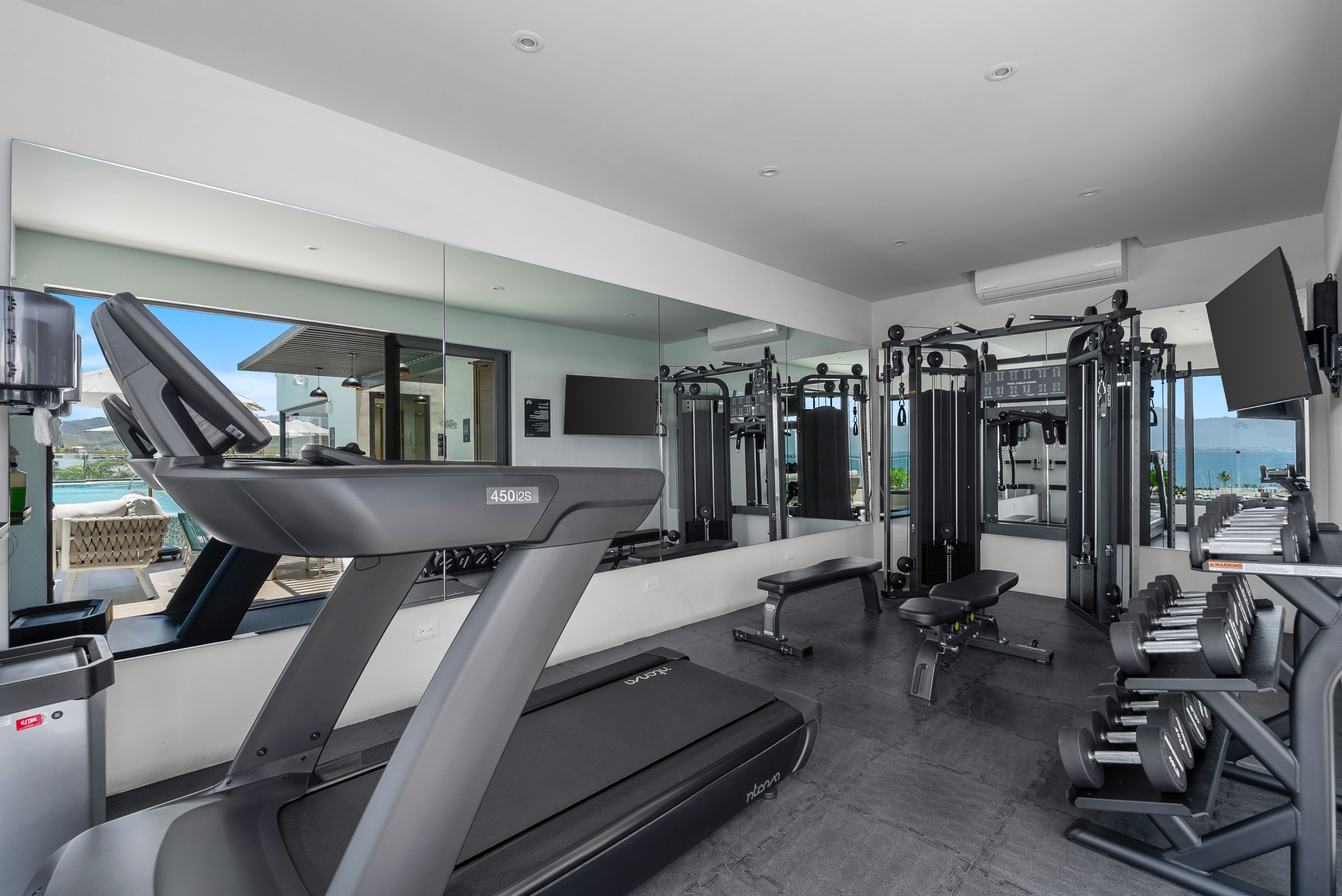 Un gimnasio moderno con una cinta de correr, máquinas de pesas y una banca.