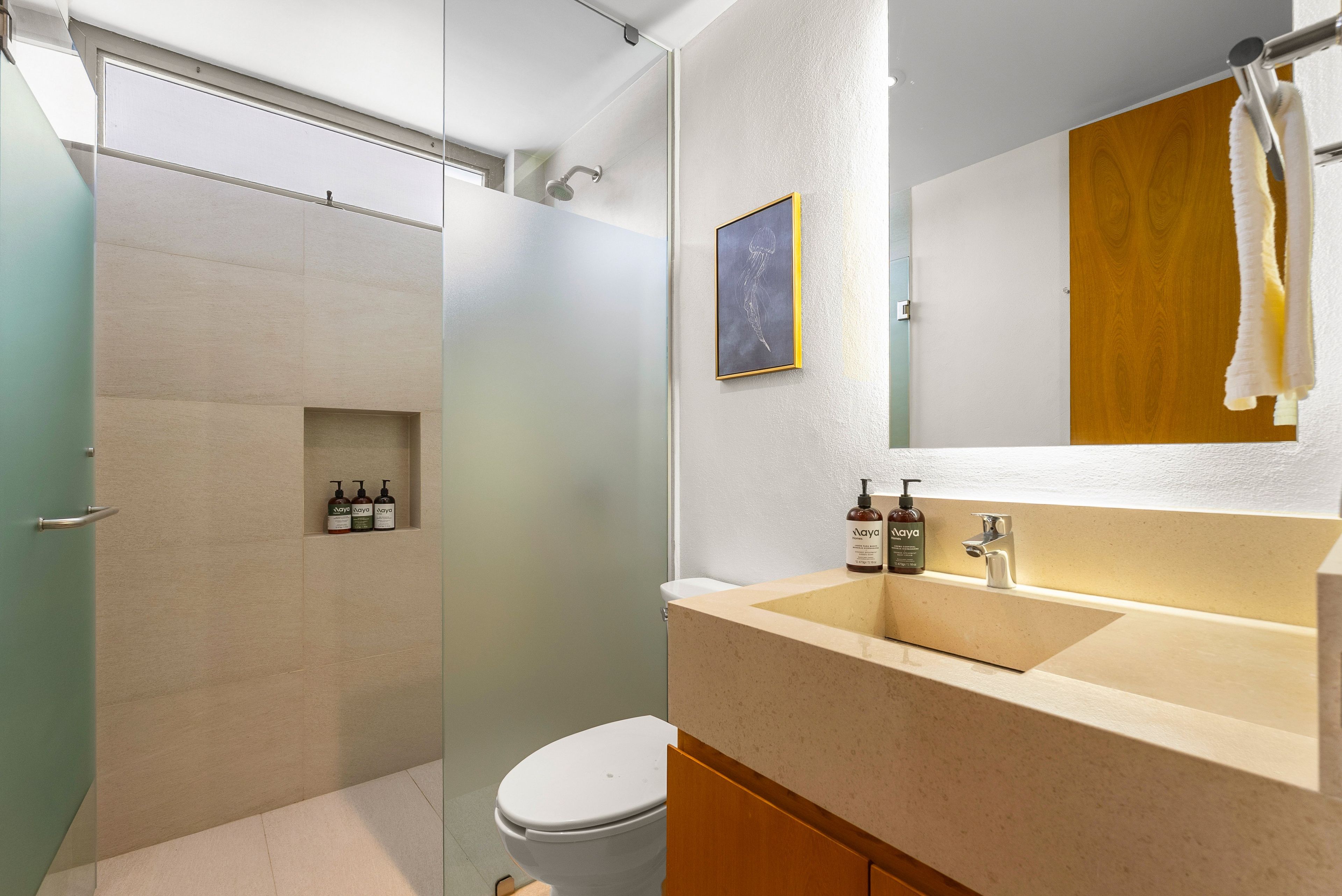 Un baño con ducha, inodoro, lavabo y un cuadro en la pared.