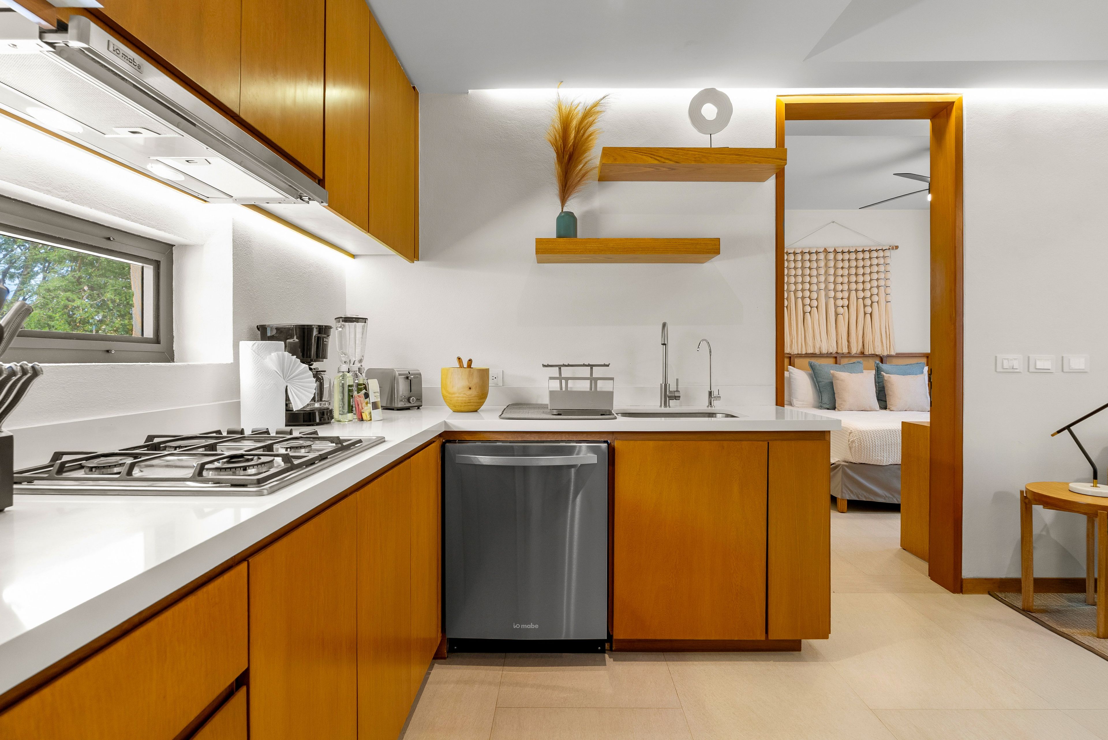 Una cocina moderna con alacenas de madera, lavavajillas y ventana.