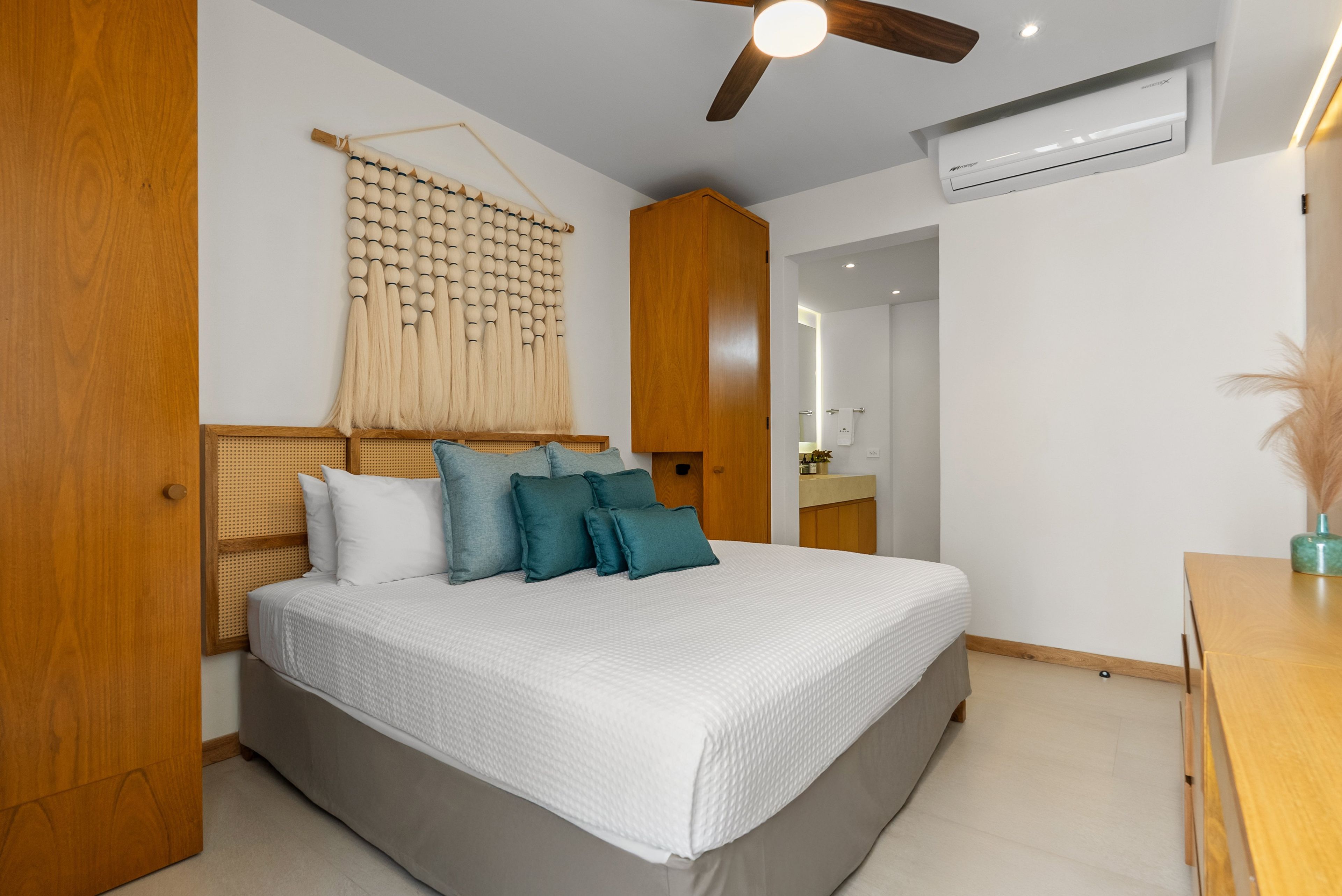 Un dormitorio con cama, ventilador de techo, aire acondicionado y armario de madera.