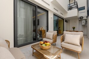 Uma área de estar moderna ao ar livre, com móveis de vime e uma cesta de frutas.