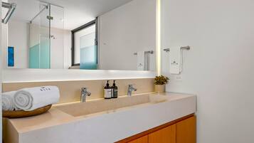 A modern bathroom with a double sink, a mirror, a towel rack, and a small plant.