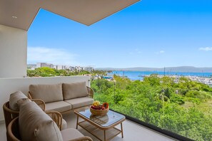 Varanda com sofá e mesa, com vista para um porto de recreio e vegetação.