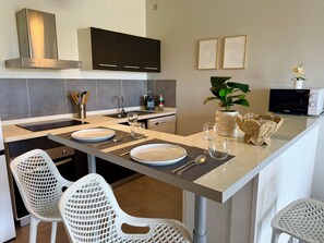 A modern kitchen with a central island, a built-in oven, and a microwave. - Spacious apartment with a garden just a stone's throw from the beach (Saint Martin)