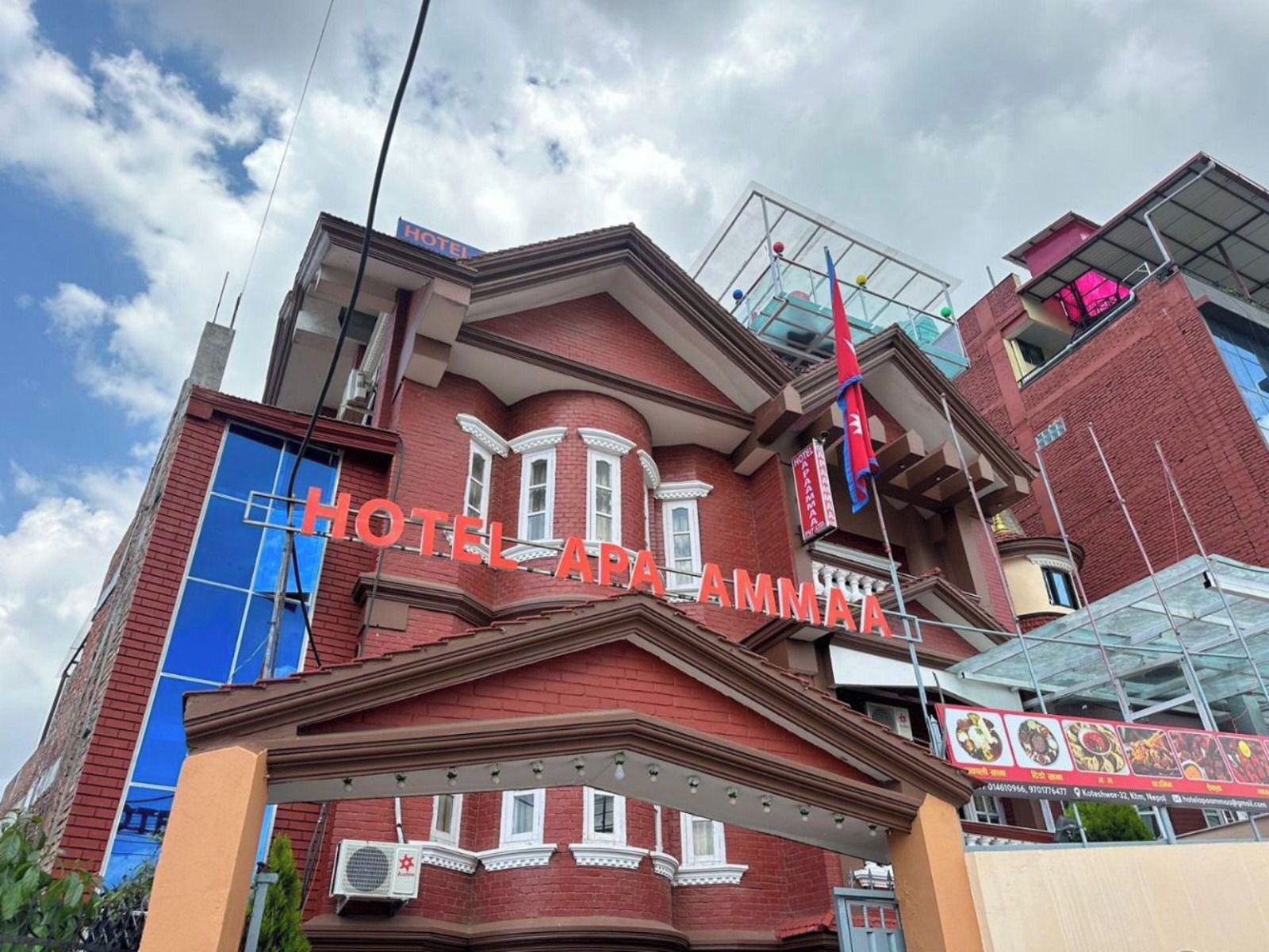 Un hotel con una fachada roja destacada, una entrada azul y un cartel con el nombre del hotel.