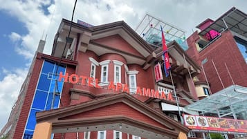 Un hotel con una fachada roja destacada, una entrada azul y un cartel con el nombre del hotel.