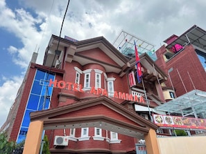 Un hotel con una fachada roja destacada, una entrada azul y un cartel con el nombre del hotel.