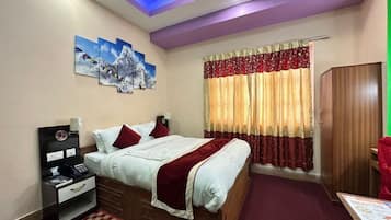 Habitación de hotel con cama, mesita de noche, lámpara, una obra de arte en la pared y una ventana con cortinas.