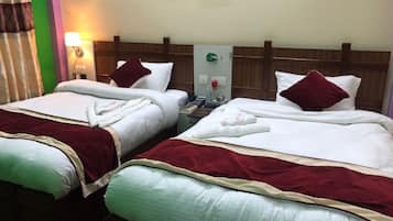 Habitación de hotel con dos camas, cada una con cubrecolcha rojo y blanco, cabecero de madera y mesita de noche con lámpara y teléfono.