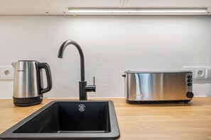 A modern kitchen with a sink, a kettle, and a toaster. - Apartment with a view of the garden & air conditioning | Danube Canal | 6 guests (Wien)