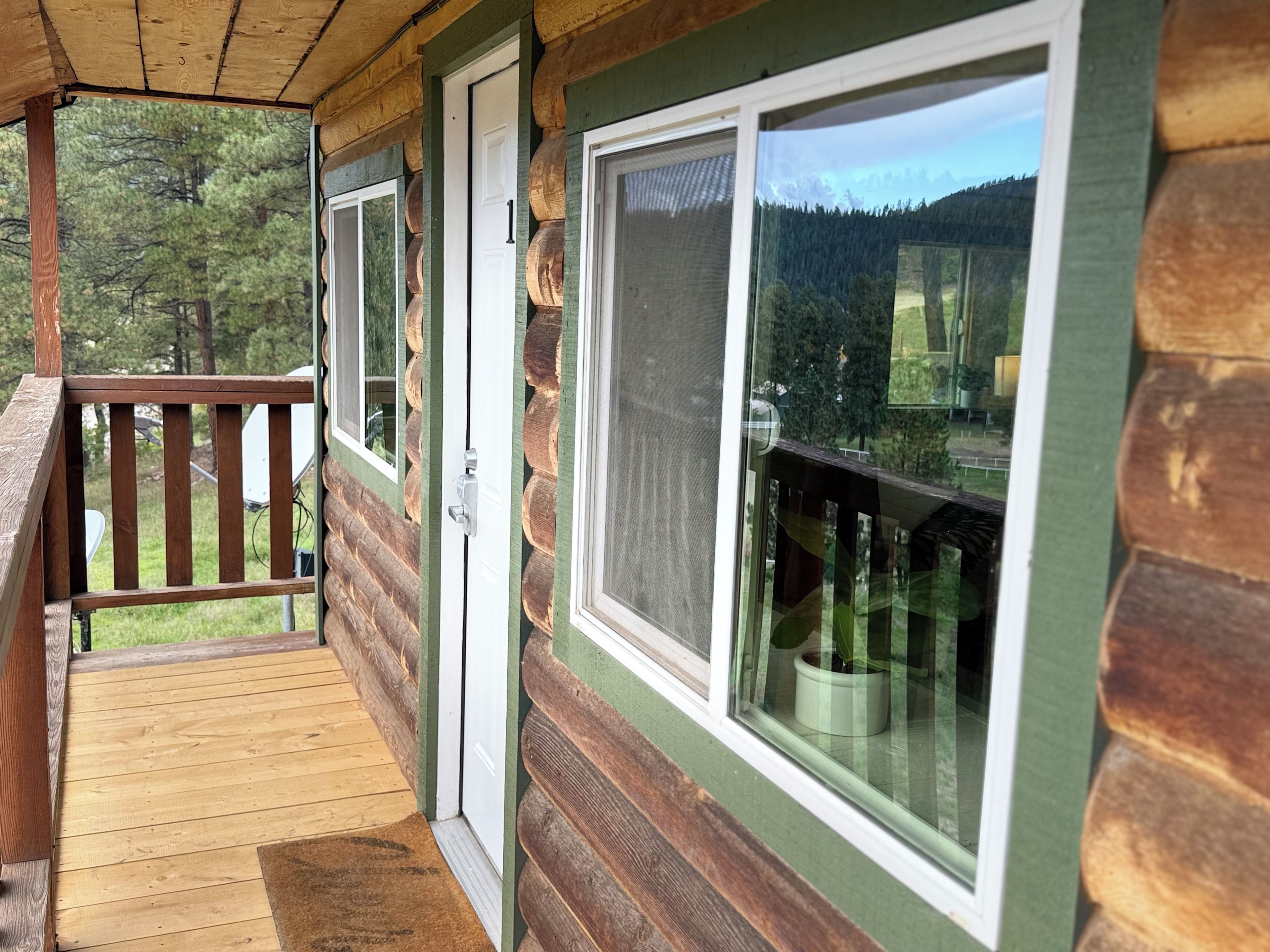 A wooden cabin with a porch, a door, and large windows.