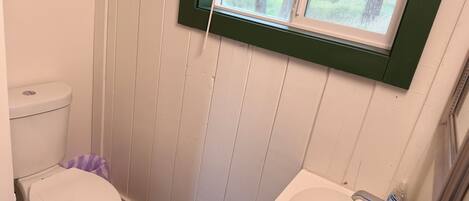Un baño pequeño con inodoro, lavamanos y ventana.