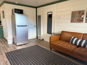 A compact living space with a kitchenette, a sofa, a patterned rug, and a wall-mounted artwork. - Your Cozy Studio with Open Scenic Views & Pine Surroundings (Bayfield)