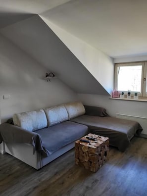 A modern living room with a gray sofa, a wooden coffee table, and a sloped ceiling. - Two Bedroom Soul with Free Parking (Kranjska Gora)