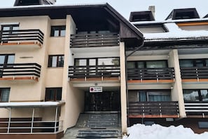 A multi-story building with balconies, a sign indicating a parking area, and a staircase leading to the entrance. - Two Bedroom Soul with Free Parking (Kranjska Gora)
