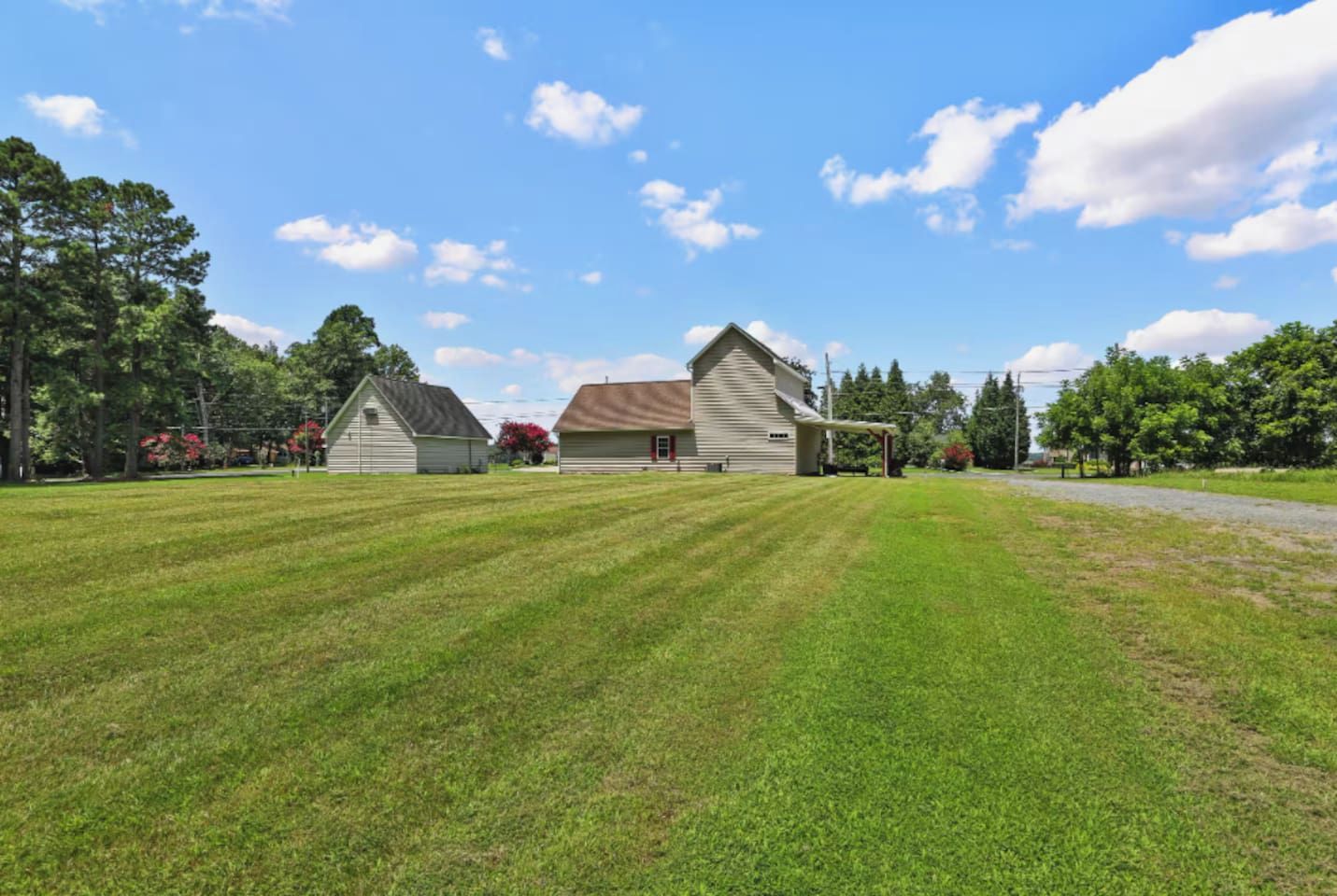 A property with a large lawn, two barns, and a clear sky.