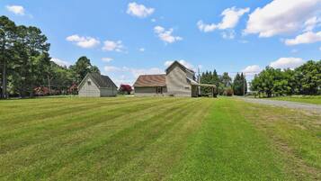 A property with a large lawn, two barns, and a clear sky.