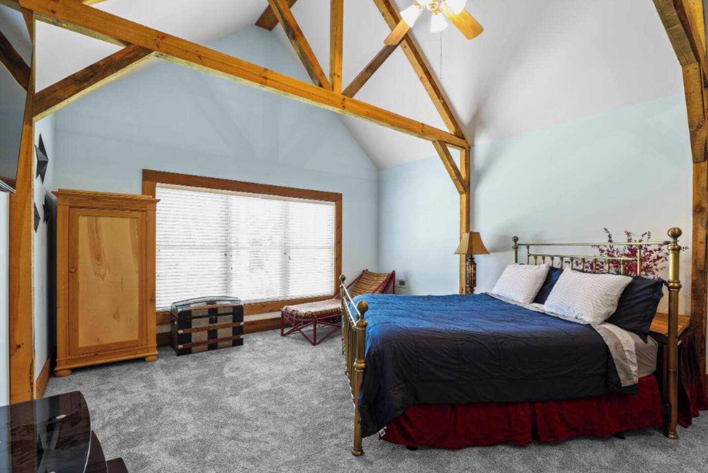 A bedroom with a bed, a window, a wardrobe, and a chair.