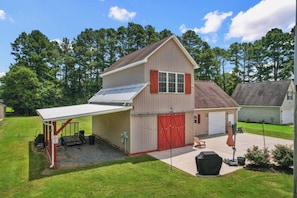 A two-story house with a garage, a covered porch, and a small patio area.